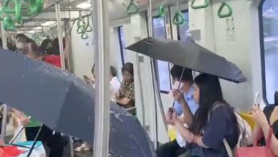 Penumpang guna payung dalam tren